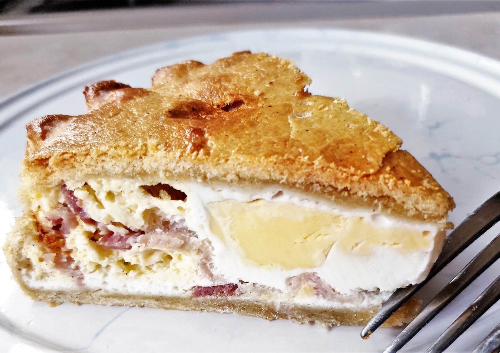 Top-down view of a freshly baked bacon and egg pie on a wooden board