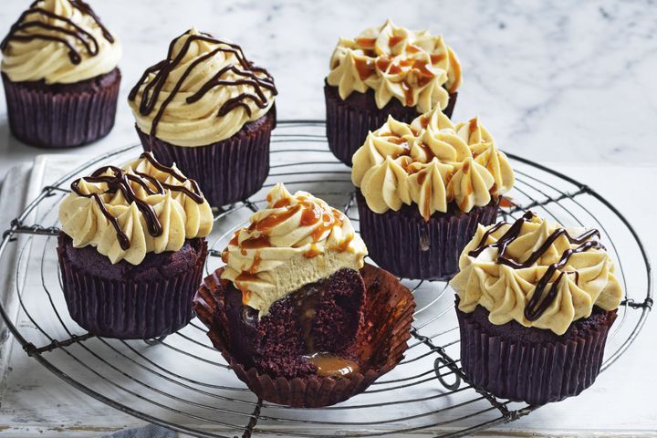 Close-up of crunchy chocolate Rolo cupcakes topped with caramel frosting and biscuit crumbs.